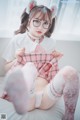 A woman sitting on top of a bed wearing a pink and white outfit.