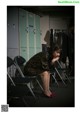 A woman sitting on a chair in front of lockers.