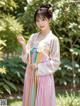 A woman in a pink and yellow hanbok poses for a picture.