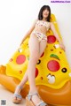 A woman in a bikini sitting on an inflatable pizza slice.