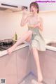 A woman sitting on a kitchen counter holding a bowl of food.