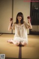 A woman sitting on a tatami mat holding a red rose.