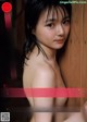 A naked asian woman leaning against a wooden wall.