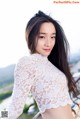 A woman in a white lace top posing for a picture.