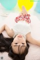 A little girl laying on a pink blanket with balloons.