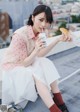 A woman sitting on a ledge eating a sandwich and drinking milk.