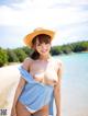 A woman in a straw hat is posing on the beach.