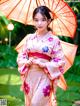 A woman in a kimono holding an orange umbrella.