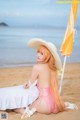 A woman in a pink bikini sitting on the beach.